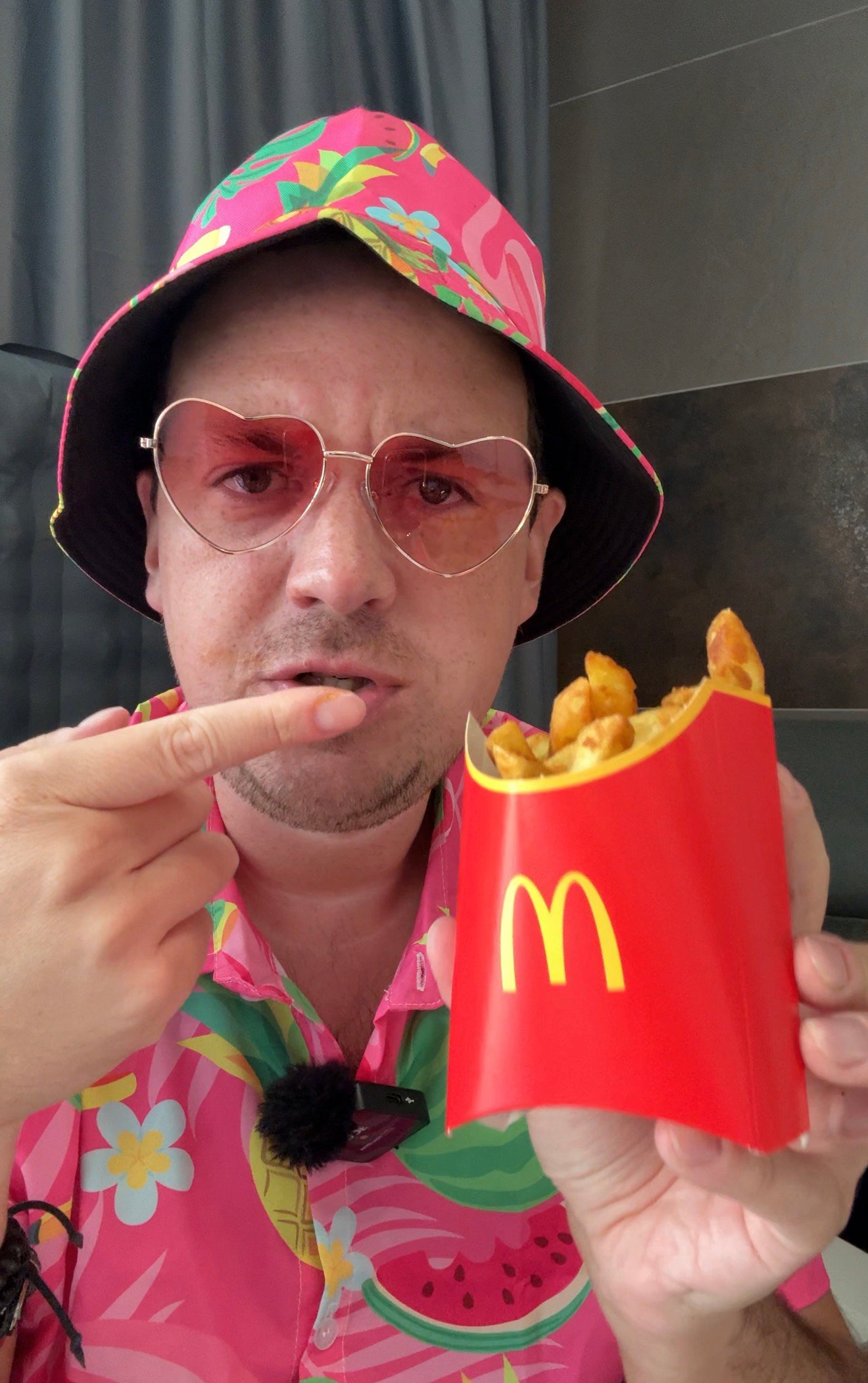 Markus im pinken Urlaubsoutfit mit Hut, Herz-Sonnenbrille und Pommes